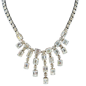 Close-up of a vintage silver-tone collar necklace featuring a cascading fringe of emerald-cut clear rhinestones against a white background