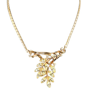 Gold necklace with leaf-shaped pendant on a white background