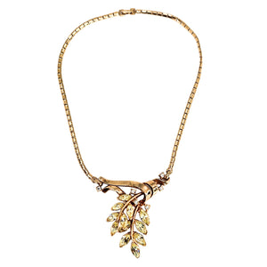 Gold necklace with leaf-shaped pendant on a white background