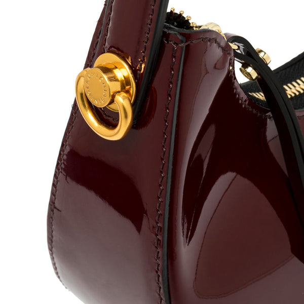 Close-up of a dark red handbag with a gold clasp on a white background