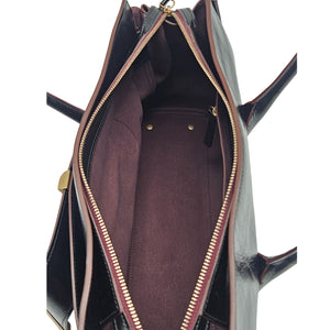 A sleek, black leather handbag with two slender top handles and a horizontal gold bar accent on the front.
