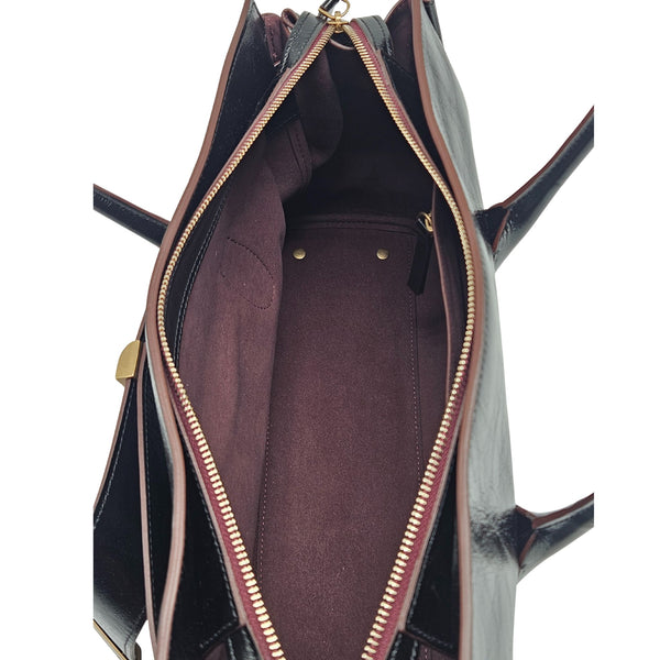 A sleek, black leather handbag with two slender top handles and a horizontal gold bar accent on the front.