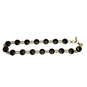 Gold bracelet with black beads on a white background