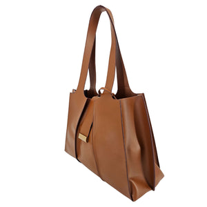 A mid-brown polished leather handbag with a wide opening, two top handles, a horizontal gold bar accent on the front, and a matching small brown pouch resting in front of it.