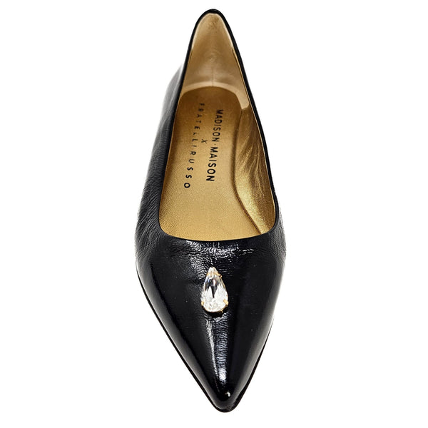 Black pointed-toe shoe with a crystal detail on a white background