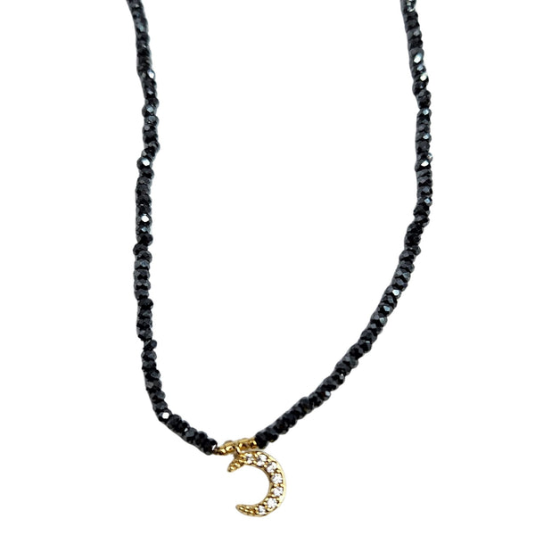 Black beaded necklace with a gold crescent moon charm on a white background