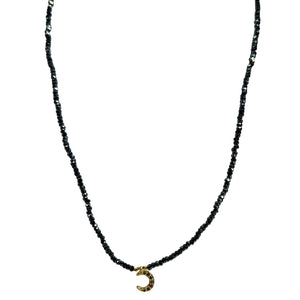 Black beaded necklace with a gold crescent moon pendant on a white background
