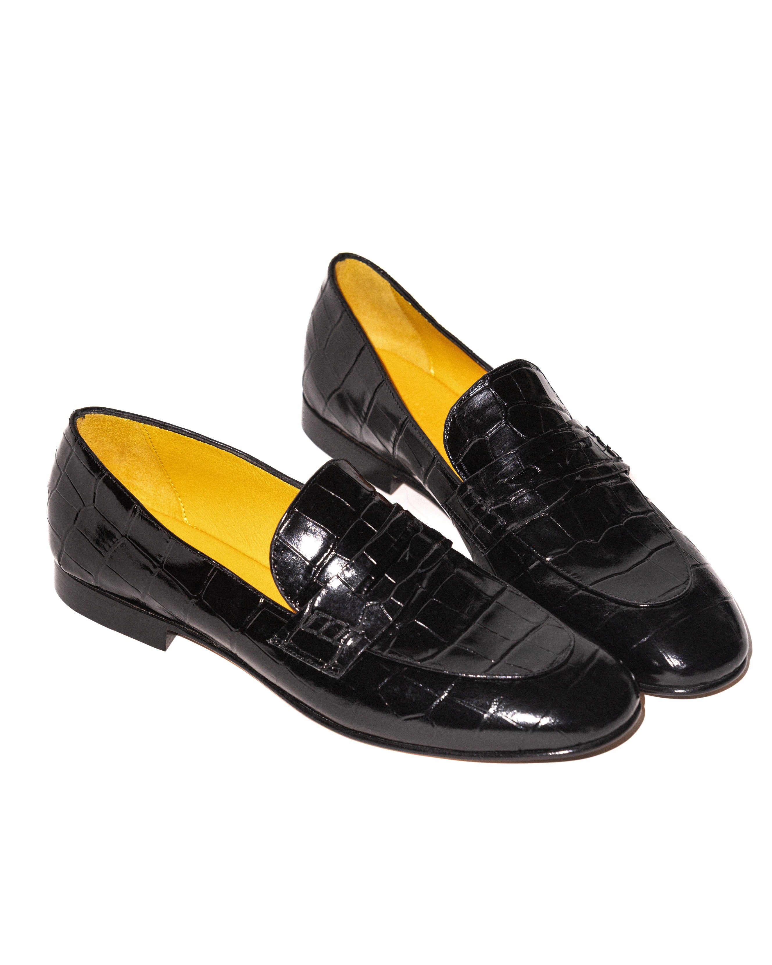 Black crocodile-patterned loafers with yellow lining on a white background