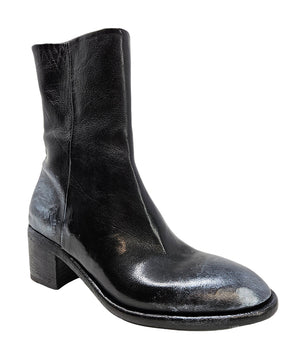 Mid-heel ankle boot crafted from premium leather with a softly rounded toe, artisanal distressed detailing at the toe and heel, and a stacked block heel. Features a full side zipper for easy entry, a leather-lined interior for comfort, and a durable leath