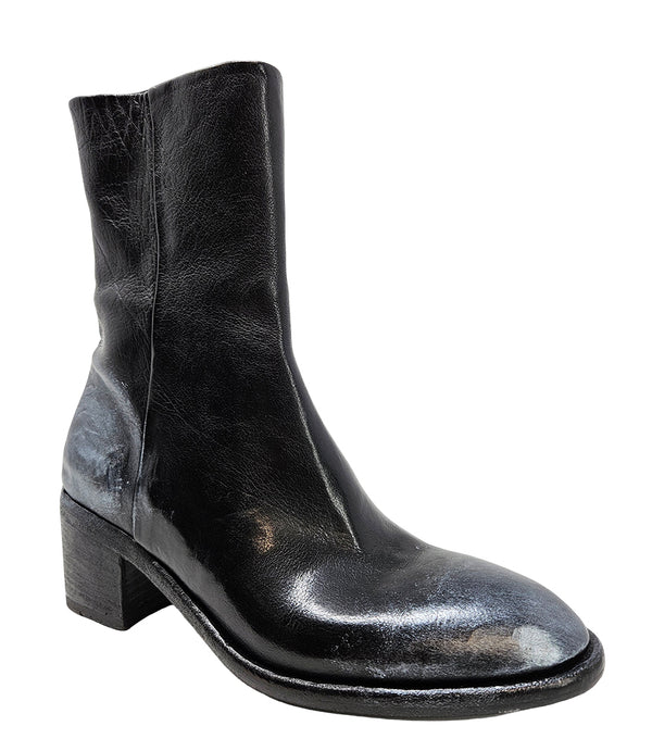 Mid-heel ankle boot crafted from premium leather with a softly rounded toe, artisanal distressed detailing at the toe and heel, and a stacked block heel. Features a full side zipper for easy entry, a leather-lined interior for comfort, and a durable leath