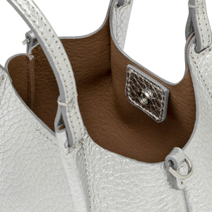 Close-up of a white leather handbag with brown interior and silver hardware.
