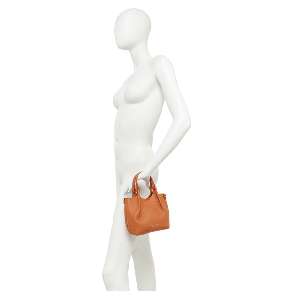 Mannequin holding an orange handbag on a white background