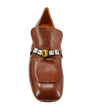A leather heeled loafer with a block heel and square toe, featuring a decorative band with faceted gemstone-style embellishments across the upper. Designed by Madison in Beverly Hills and handcrafted in Italy.