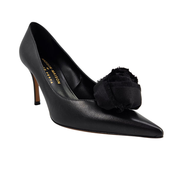 Black leather pointed-toe heel pump with large fabric flower detail at the front.