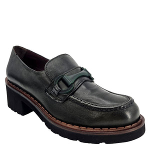 A close-up, eye-level shot of a single dark green leather lug sole loafer. The shoe features a chunky black lug sole with a visible brown welt stitching. A dark green rubber horse bit buckle adorns the vamp. The leather has a subtle pebbled texture. The background is solid white, emphasizing the shoe.