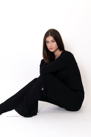 Woman wearing a black outfit sitting on a white background