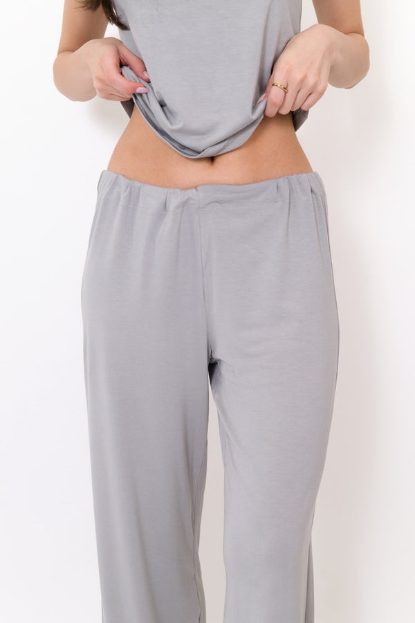 Person wearing light gray pants and a matching top on a white background