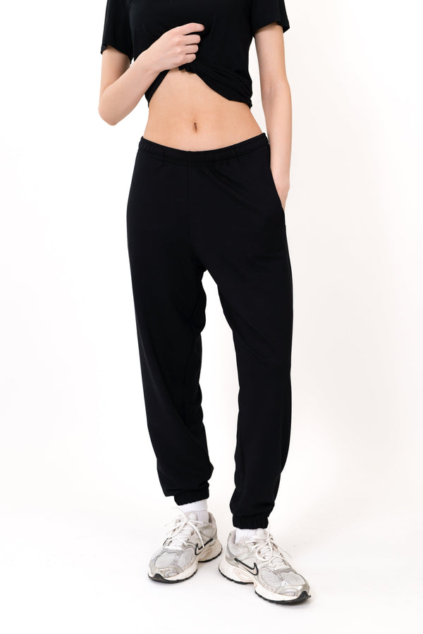 Model wearing The Solace Sweatpant in Onyx by ON/OFF Essentials, made from 95% bamboo fleece.