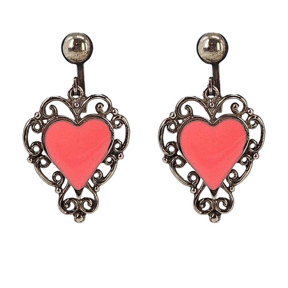 Gold-tone heart dangle earrings with pink enamel heart and ornate filigree frames.
