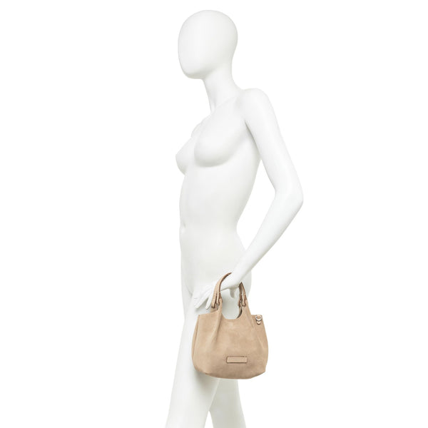 Mannequin holding a beige handbag against a white background