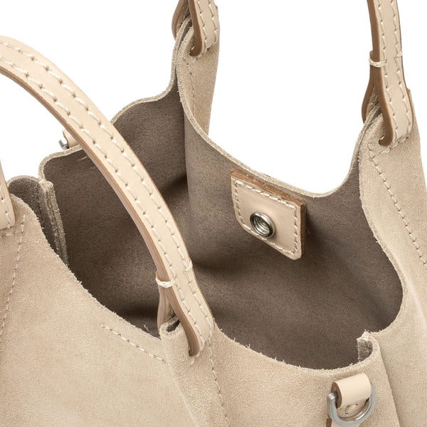 Close-up of a beige handbag with a visible brand logo on a white background