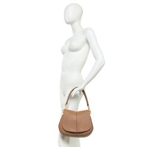 Mannequin holding a brown handbag against a white background