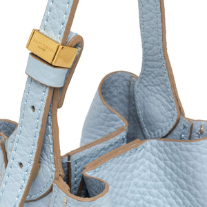 Close-up of a light blue textured handbag with a gold clasp on a white background