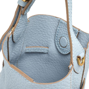 Close-up of a light blue handbag with gold accents on a white background