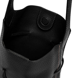 Close-up of a black leather bag with visible stitching on a white background