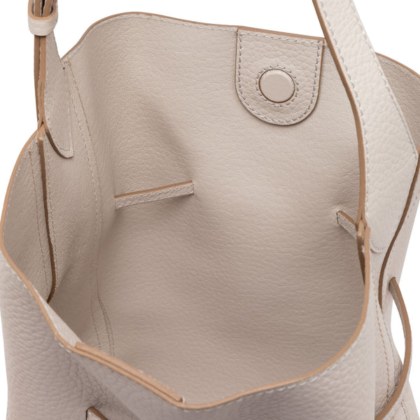 Close-up of a beige leather handbag with a strap on a white background