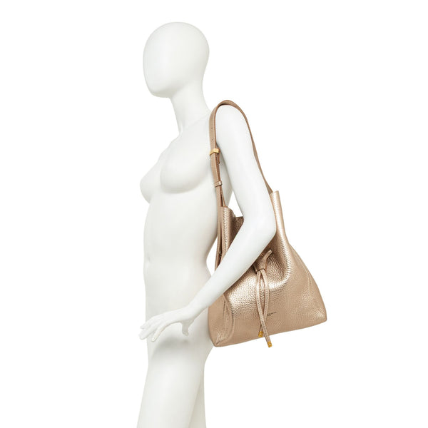 Mannequin holding a gold handbag against a white background