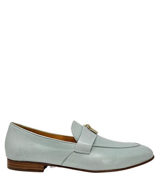 A leather loafer with a flat sole and rounded toe, featuring a small metal lock accent centered on the upper strap. Designed by Madison in Beverly Hills and handcrafted in Italy.