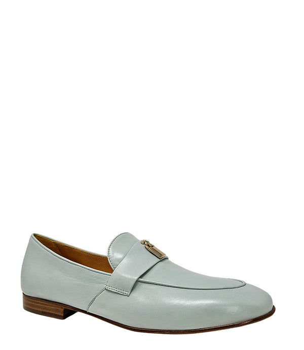 A leather loafer with a flat sole and rounded toe, featuring a small metal lock accent centered on the upper strap. Designed by Madison in Beverly Hills and handcrafted in Italy.