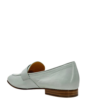 A leather loafer with a flat sole and rounded toe, featuring a small metal lock accent centered on the upper strap. Designed by Madison in Beverly Hills and handcrafted in Italy.
