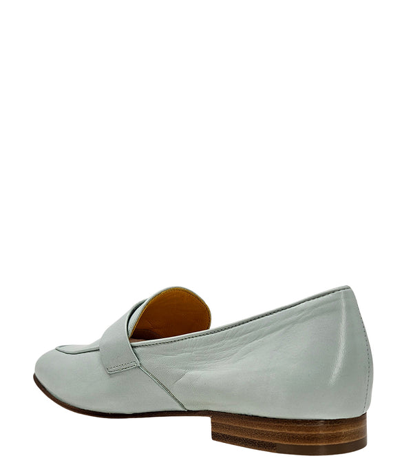 A leather loafer with a flat sole and rounded toe, featuring a small metal lock accent centered on the upper strap. Designed by Madison in Beverly Hills and handcrafted in Italy.