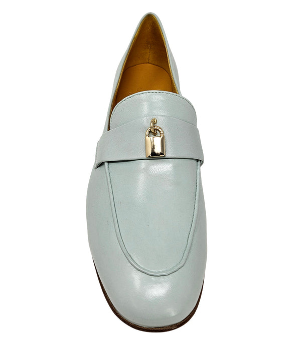 A leather loafer with a flat sole and rounded toe, featuring a small metal lock accent centered on the upper strap. Designed by Madison in Beverly Hills and handcrafted in Italy.