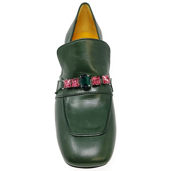 Green loafer shoe with pink gem embellishments on a white background