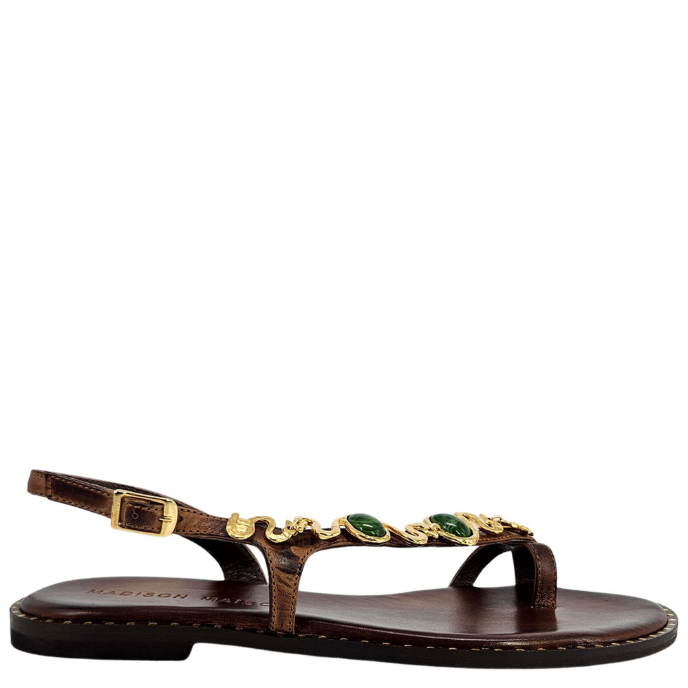 Brown sandal with gold and green embellishments on a white background