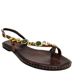 Brown sandal with gold and green embellishments on a white background