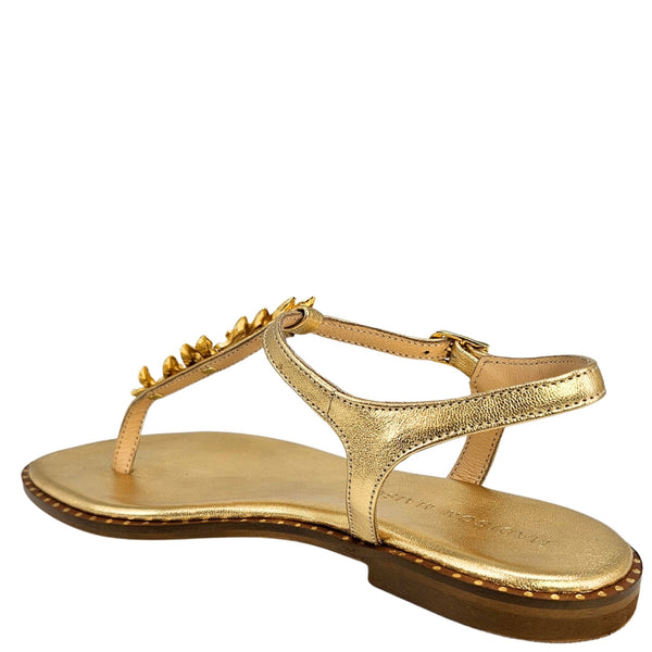 Gold sandal with decorative straps on a white background