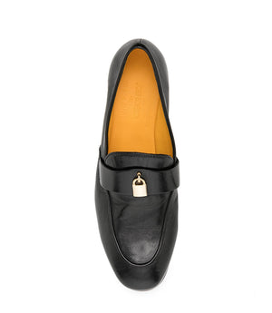 A leather loafer with a flat sole and rounded toe, featuring a small metal lock accent centered on the upper strap. Designed by Madison in Beverly Hills and handcrafted in Italy.