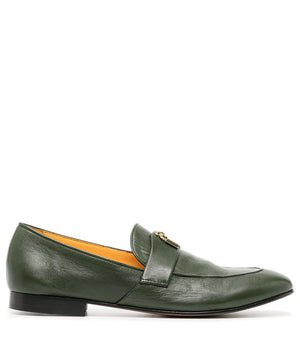 A leather loafer with a flat sole and rounded toe, featuring a small metal lock accent centered on the upper strap. Designed by Madison in Beverly Hills and handcrafted in Italy.