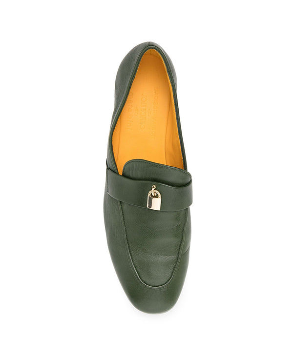 A leather loafer with a flat sole and rounded toe, featuring a small metal lock accent centered on the upper strap. Designed by Madison in Beverly Hills and handcrafted in Italy.