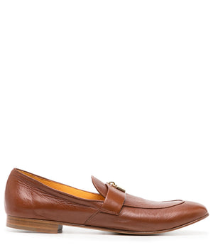 A leather loafer with a flat sole and rounded toe, featuring a small metal lock accent centered on the upper strap. Designed by Madison in Beverly Hills and handcrafted in Italy.