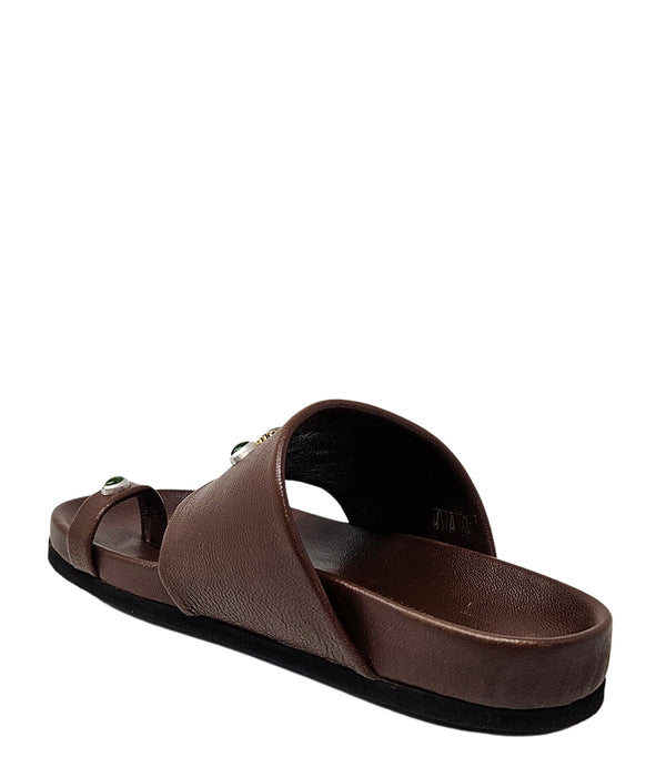 Open-toe flat sandal with a wide front strap and toe loop, embellished with central and side-set decorative stones. Features a contoured footbed and a low-profile sole.