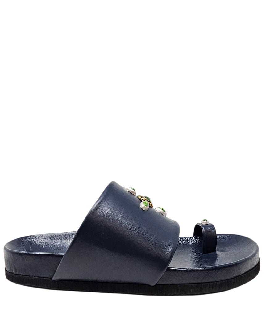 Open-toe flat sandal with a wide front strap and toe loop, embellished with central and side-set decorative stones. Features a contoured footbed and a low-profile sole.