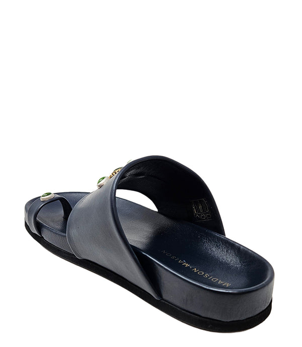 Open-toe flat sandal with a wide front strap and toe loop, embellished with central and side-set decorative stones. Features a contoured footbed and a low-profile sole.