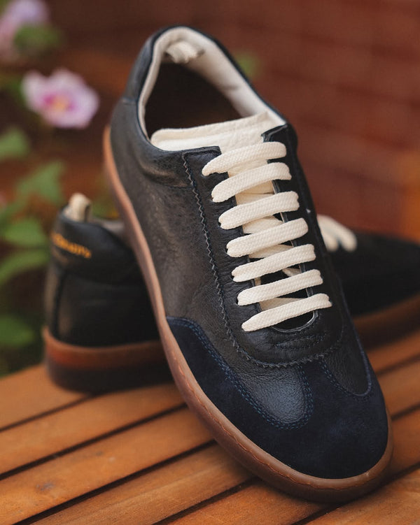 Navy blue sneakers with white laces on a wooden surface