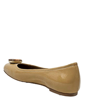 Four-angle view of a women's flat shoe with a glossy leather finish, rounded square toe, and a large faceted jewel embellishment at the toe. The shoe features a low-profile sole and a metallic-toned interior lining, displayed from side, angled, back, and