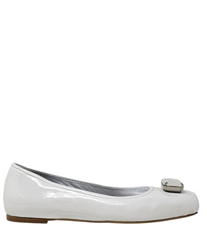 Four-angle view of a women's flat shoe with a glossy leather finish, rounded square toe, and a large faceted jewel embellishment at the toe. The shoe features a low-profile sole and a metallic-toned interior lining, displayed from side, angled, back, and
